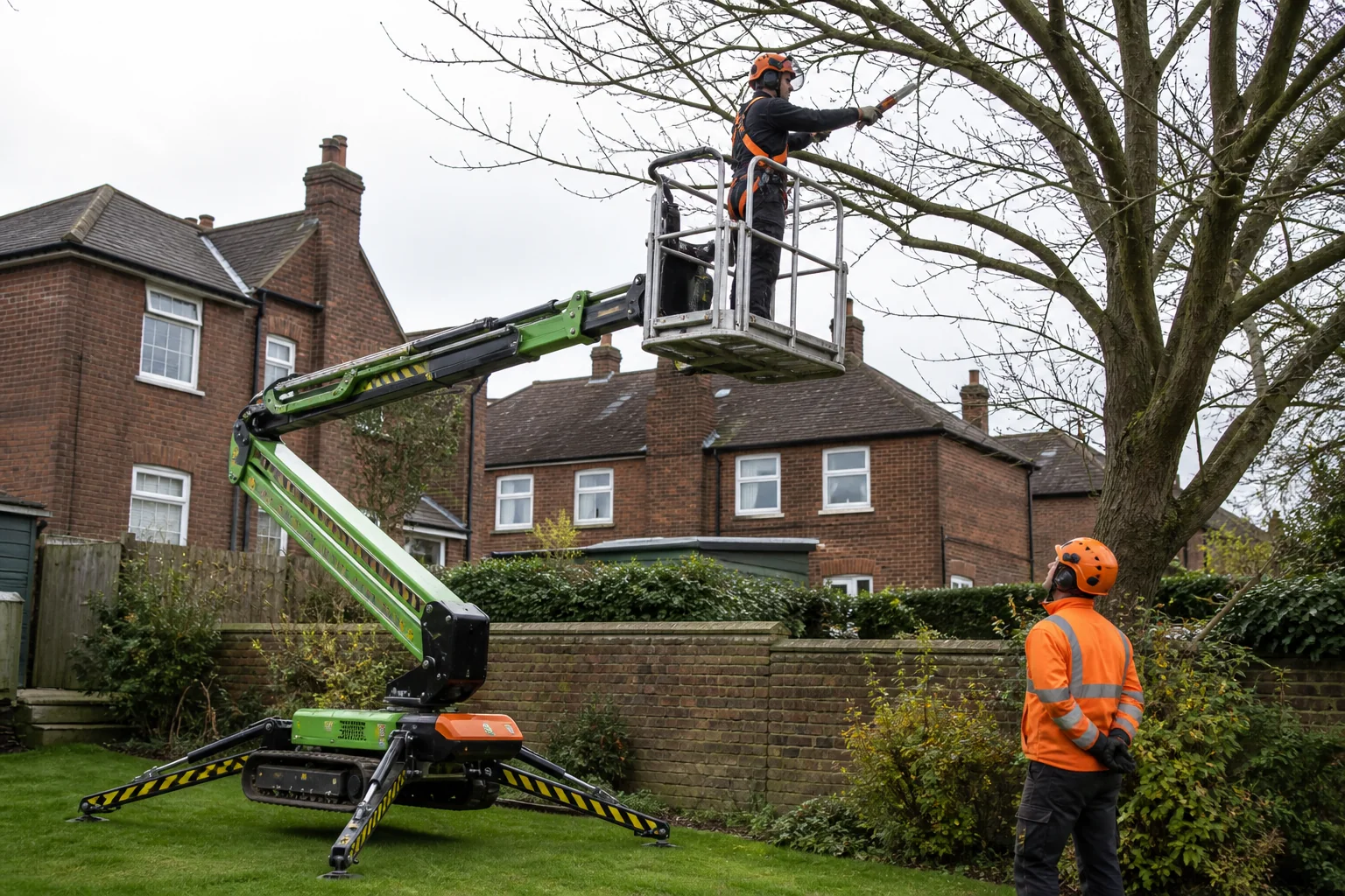 An arborist uses a hand saw from a compact tracked work platform.